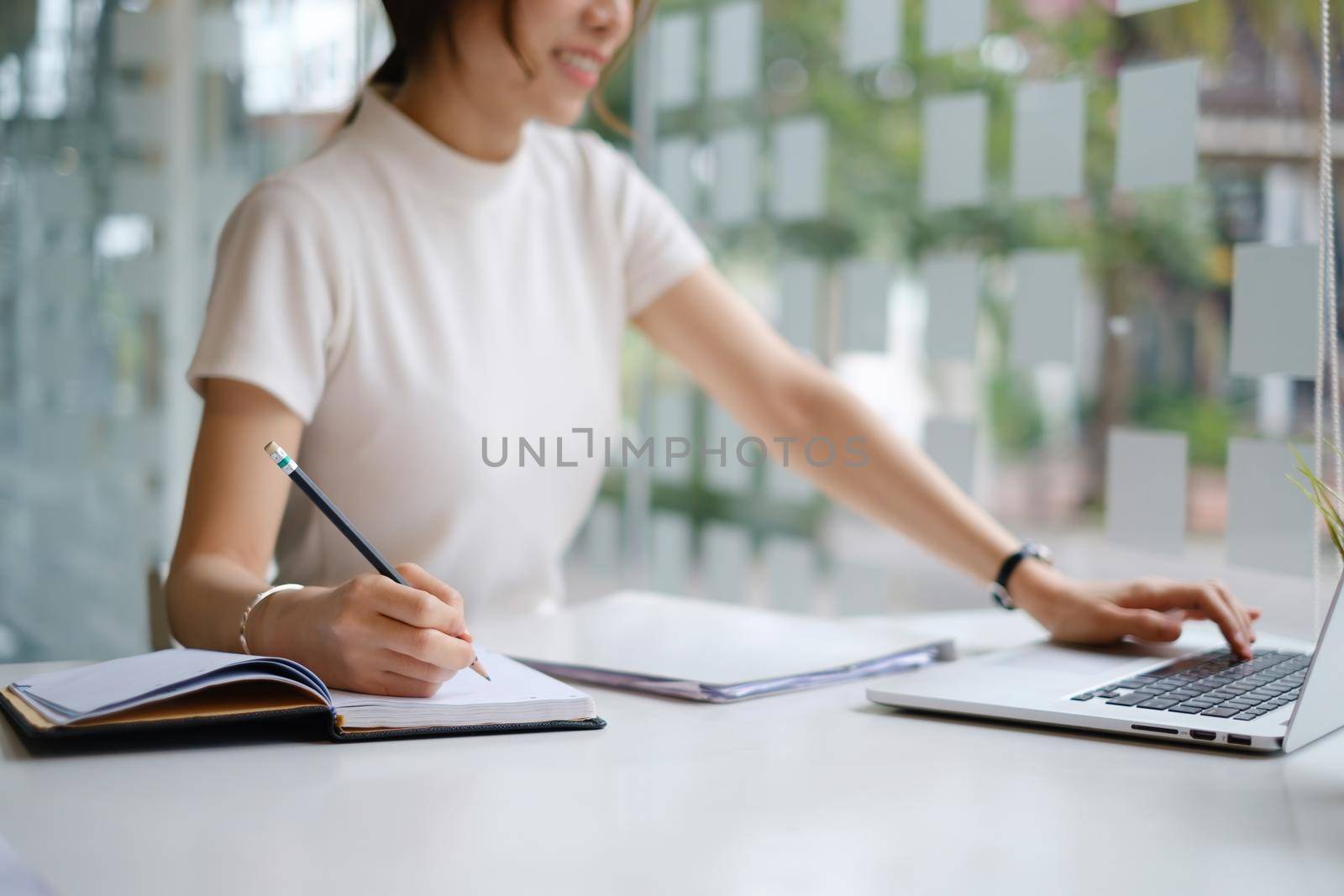 Young female college taking notes and using highlighter. Focused student in online class room. Authentic Education concept