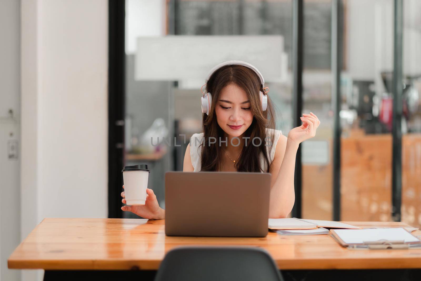 Concentrated young asian female wearing headphone and look at laptop screen for online study, attractive female student learning language, watching online webinar, e-learning education concept