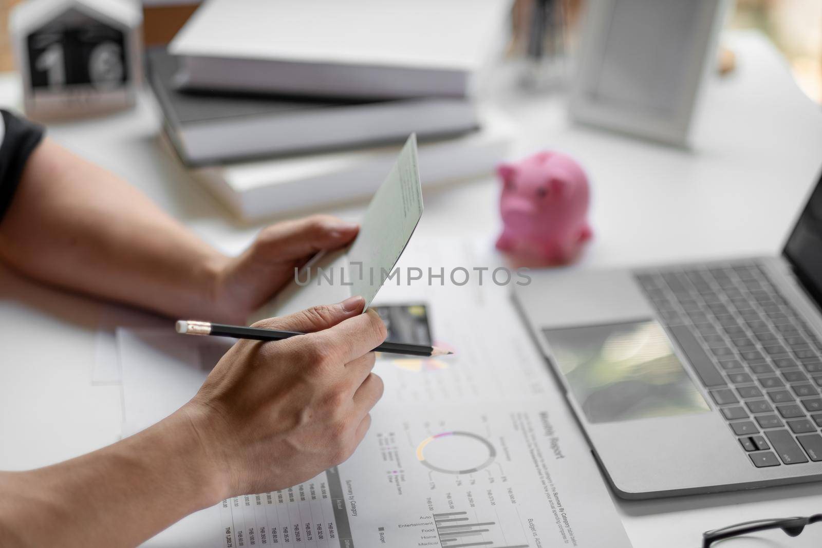 Saving and growth money concept bookkeeper using calculator, laptop computer and holding passbook to audit money account. by nateemee