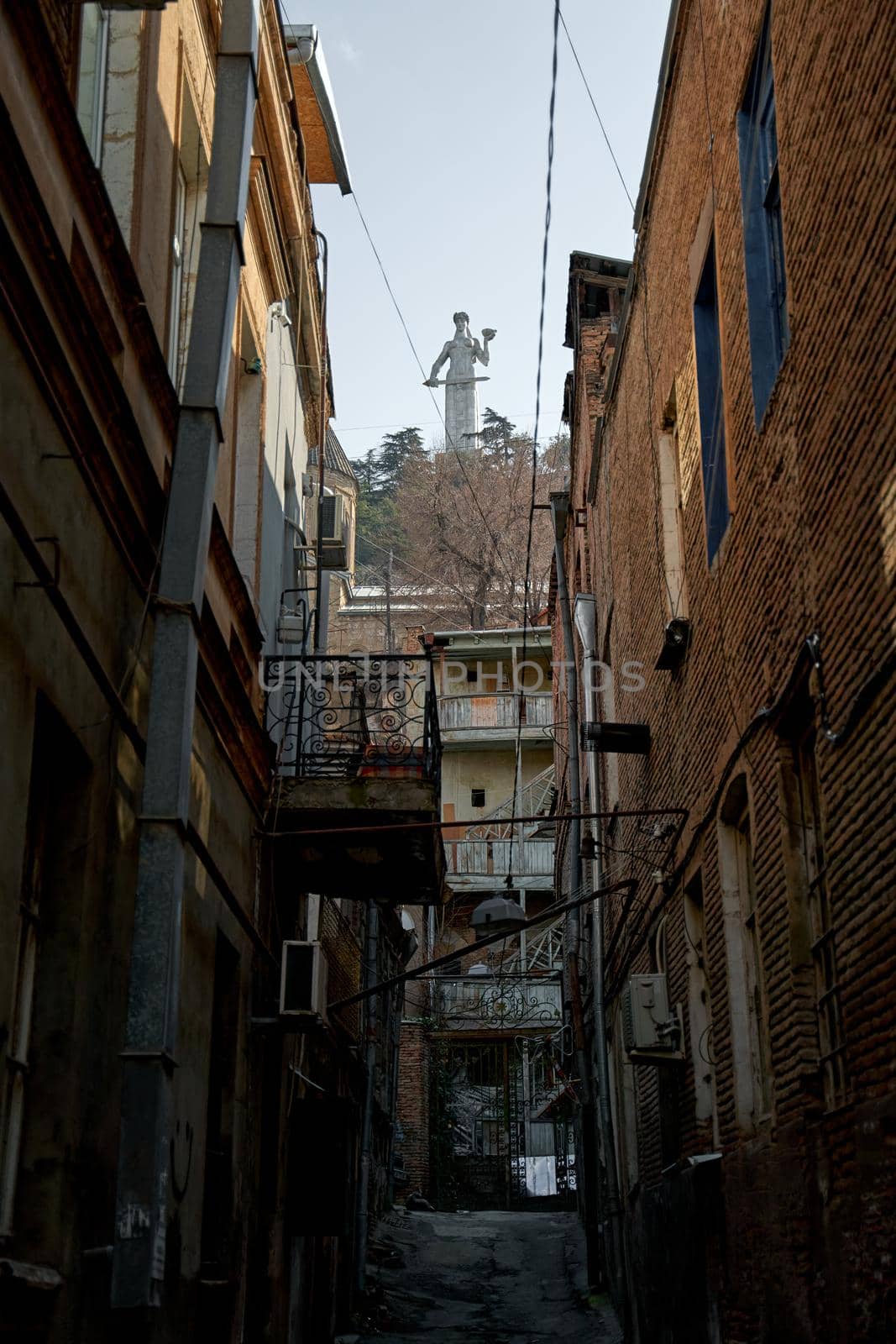 The Motherland Monument is illuminated by the sun in Tbilisi. View from the residential area.