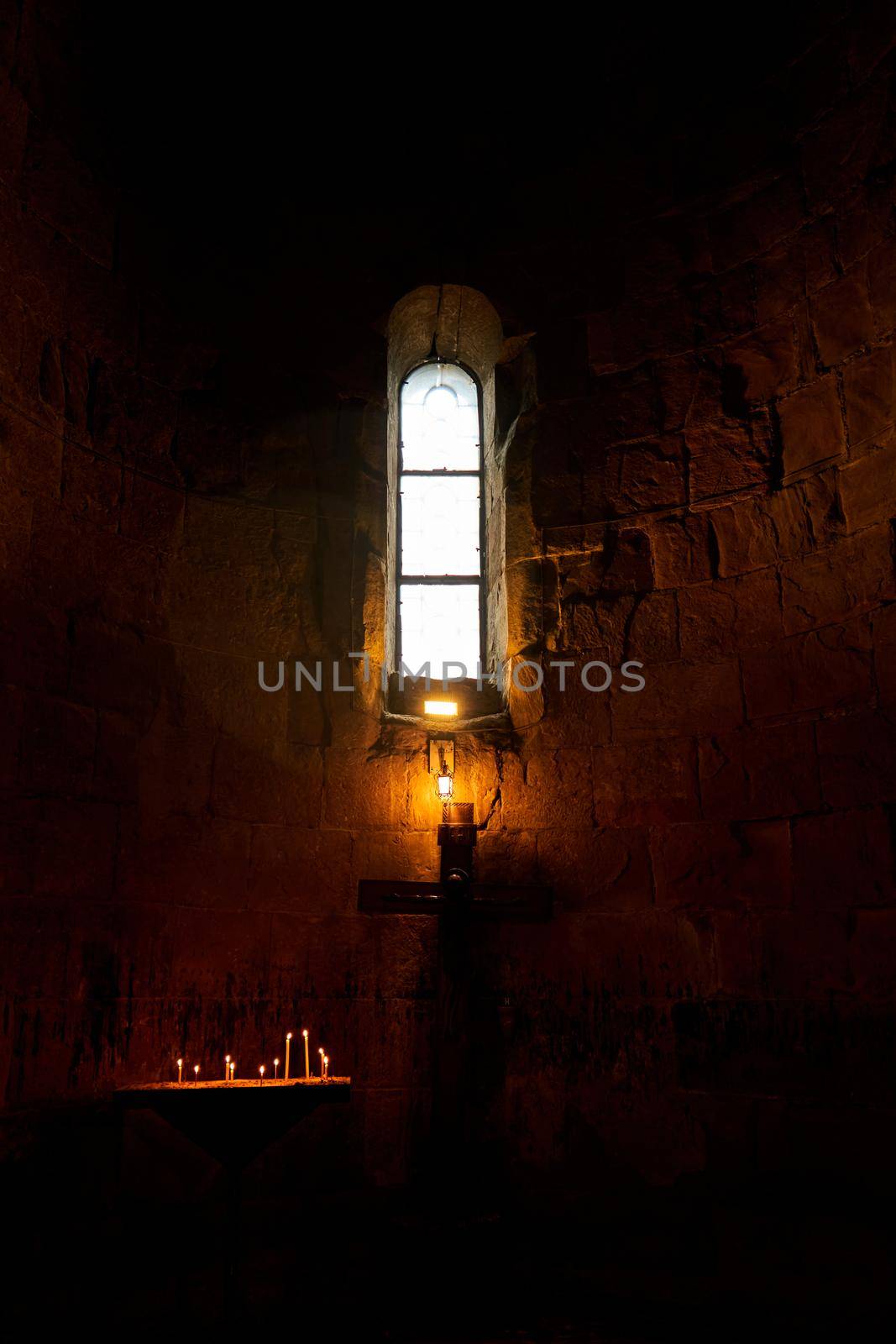 Dark temple with small windows and burning candles.