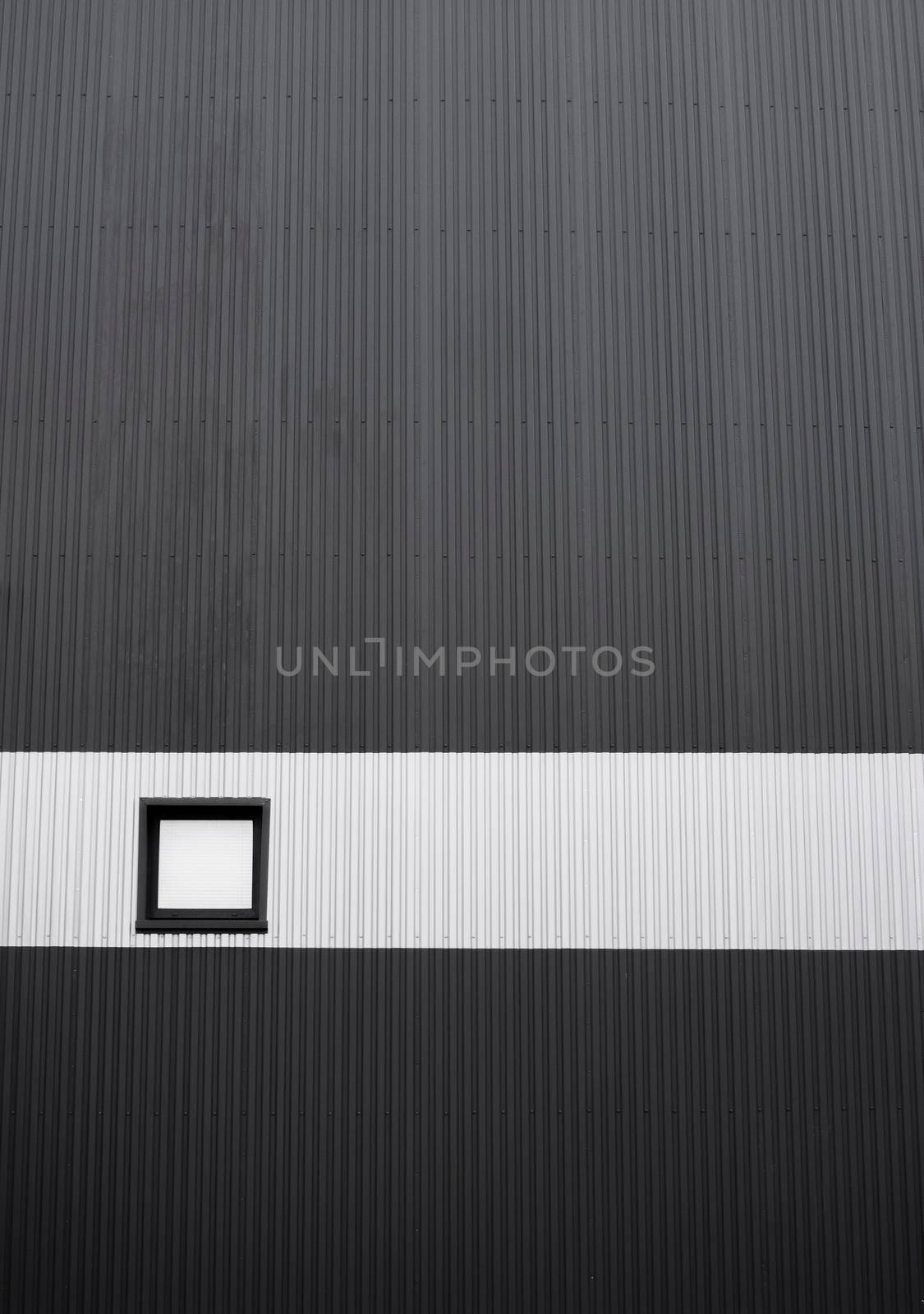 Black and white corrugated iron sheet used as a facade of a warehouse or factory with a window. Texture of a seamless corrugated zinc sheet metal aluminum facade. Architecture. Metal texture