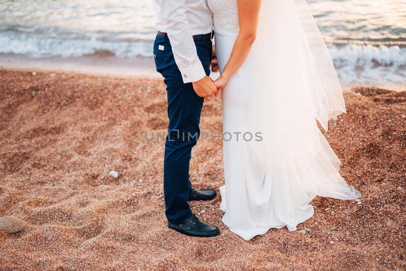 Women's and men's feet in the sand. Wedding in Montenegro
