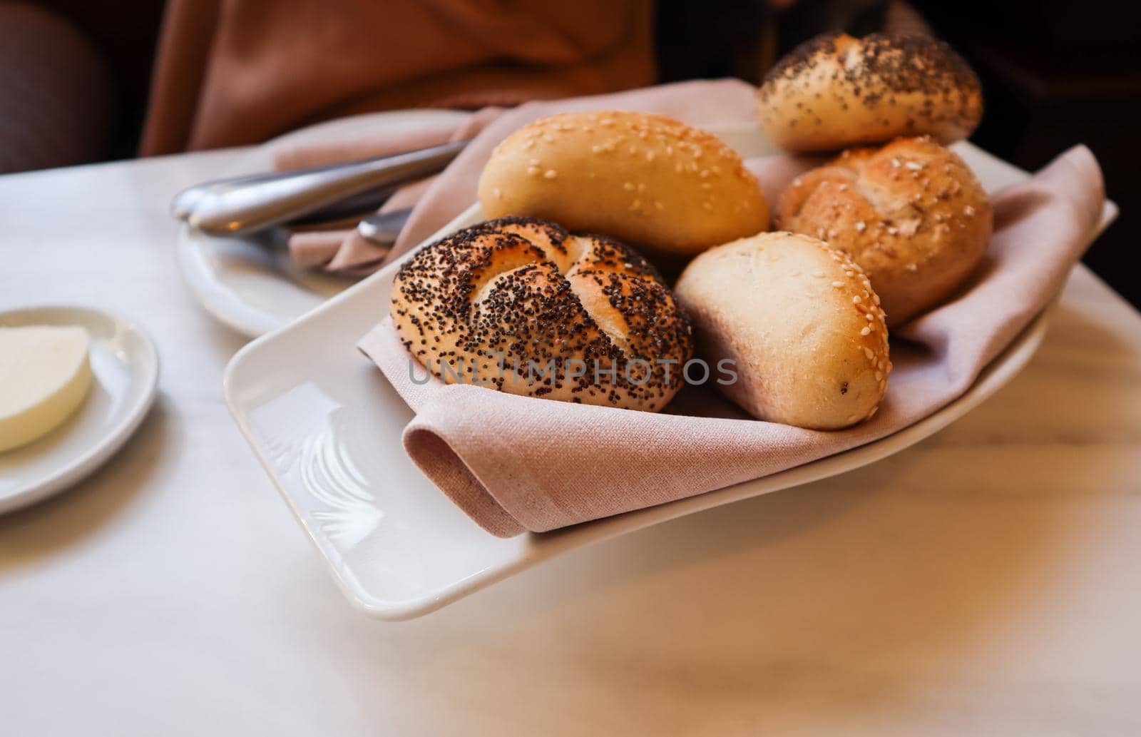 Fresh bread on a white plate with a napkin. Table setting in a restaurant