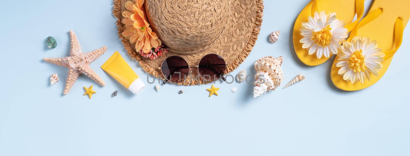 Summer beach background design concept. Top view of holiday travel with shells, hat, slipper on blue background.