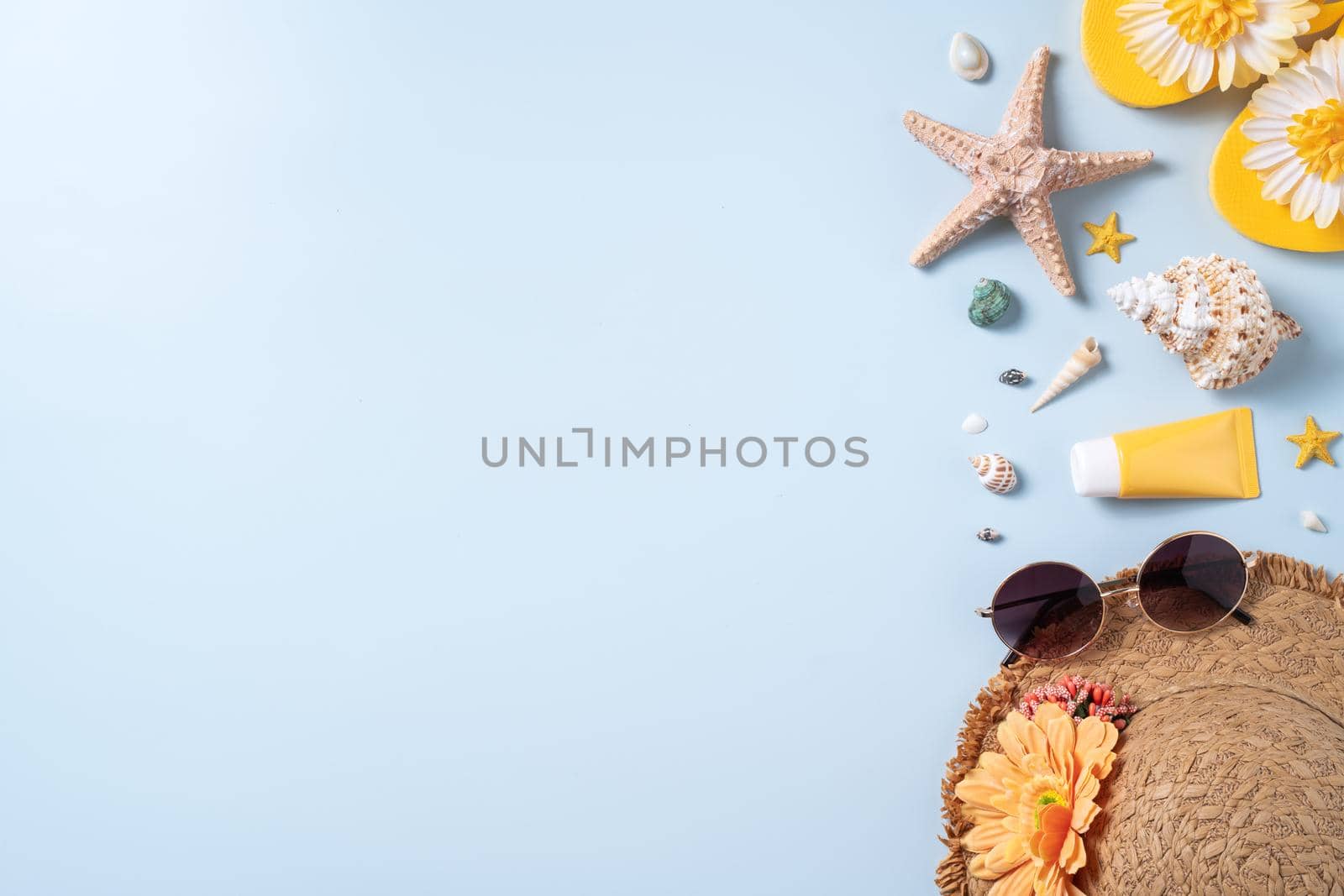 Summer beach background design concept. Top view of holiday travel with shells, hat, slipper on blue background.