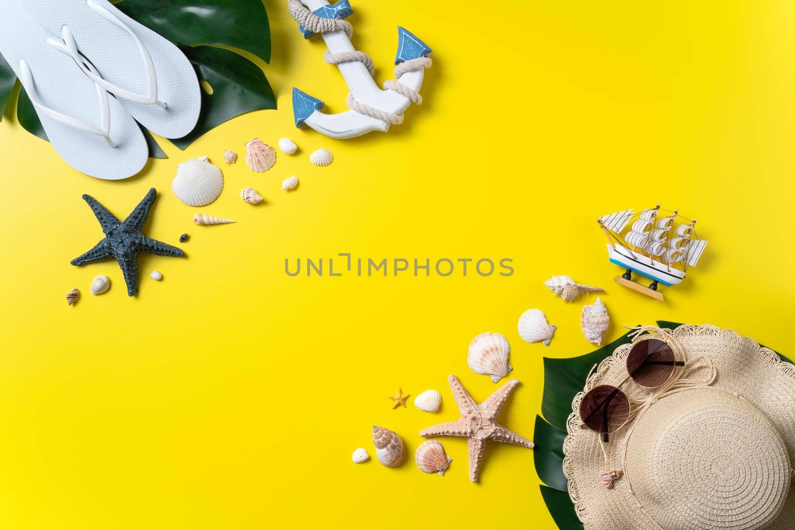 Summer beach design concept. Top view of holiday travel with shells, hat, slipper on yellow background.