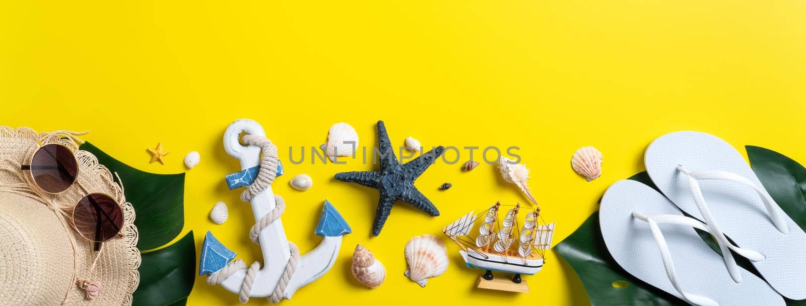 Summer beach design concept. Top view of holiday travel with shells, hat, slipper on yellow background.