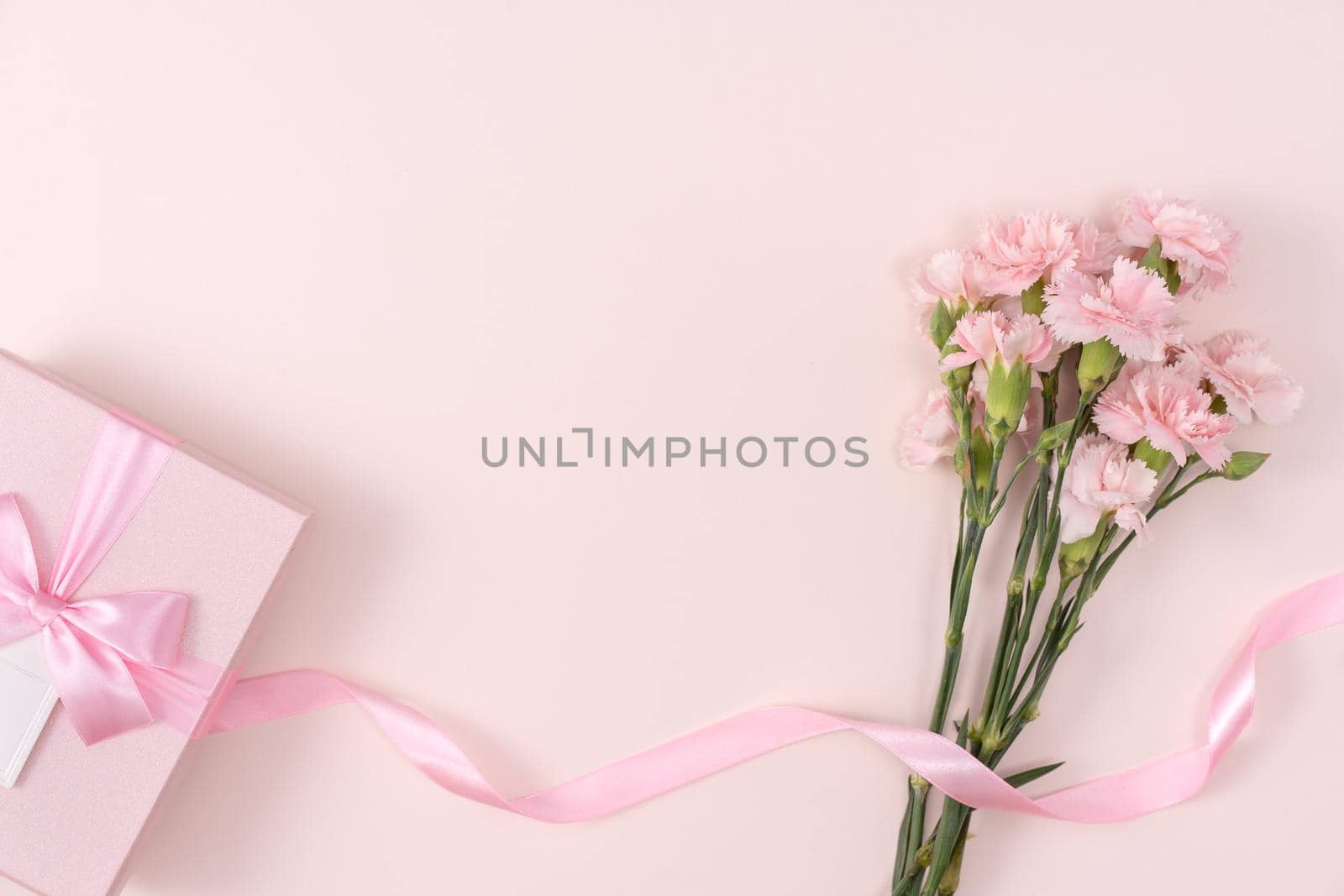 Mother's day background concept. Top view design of holiday greeting gift with carnation bouquet on bright pink table background