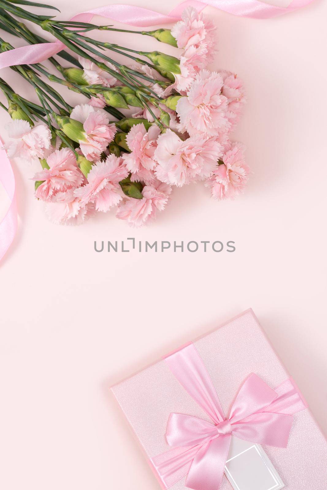 Mother's day background concept. Top view design of holiday greeting gift with carnation bouquet on bright pink table background