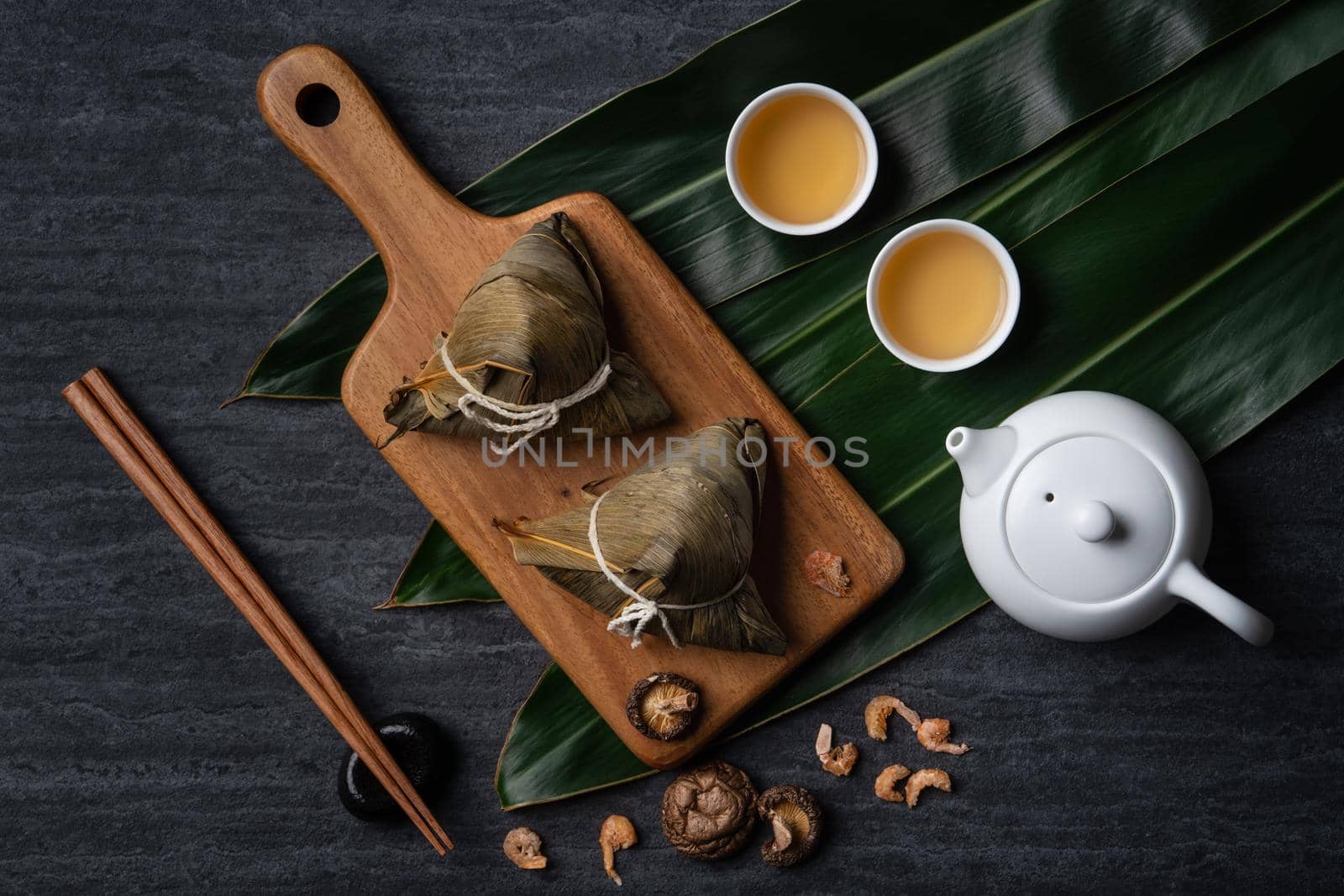 Zongzi. Rice dumpling top view design concept for Chinese traditional Dragon Boat Festival (Duanwu Festival) over dark black slate background.