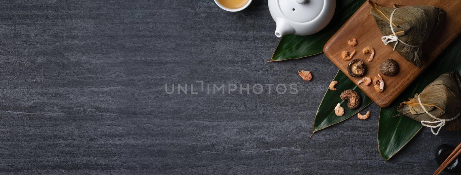 Zongzi. Rice dumpling top view design concept for Chinese traditional Dragon Boat Festival (Duanwu Festival) over dark black slate background.
