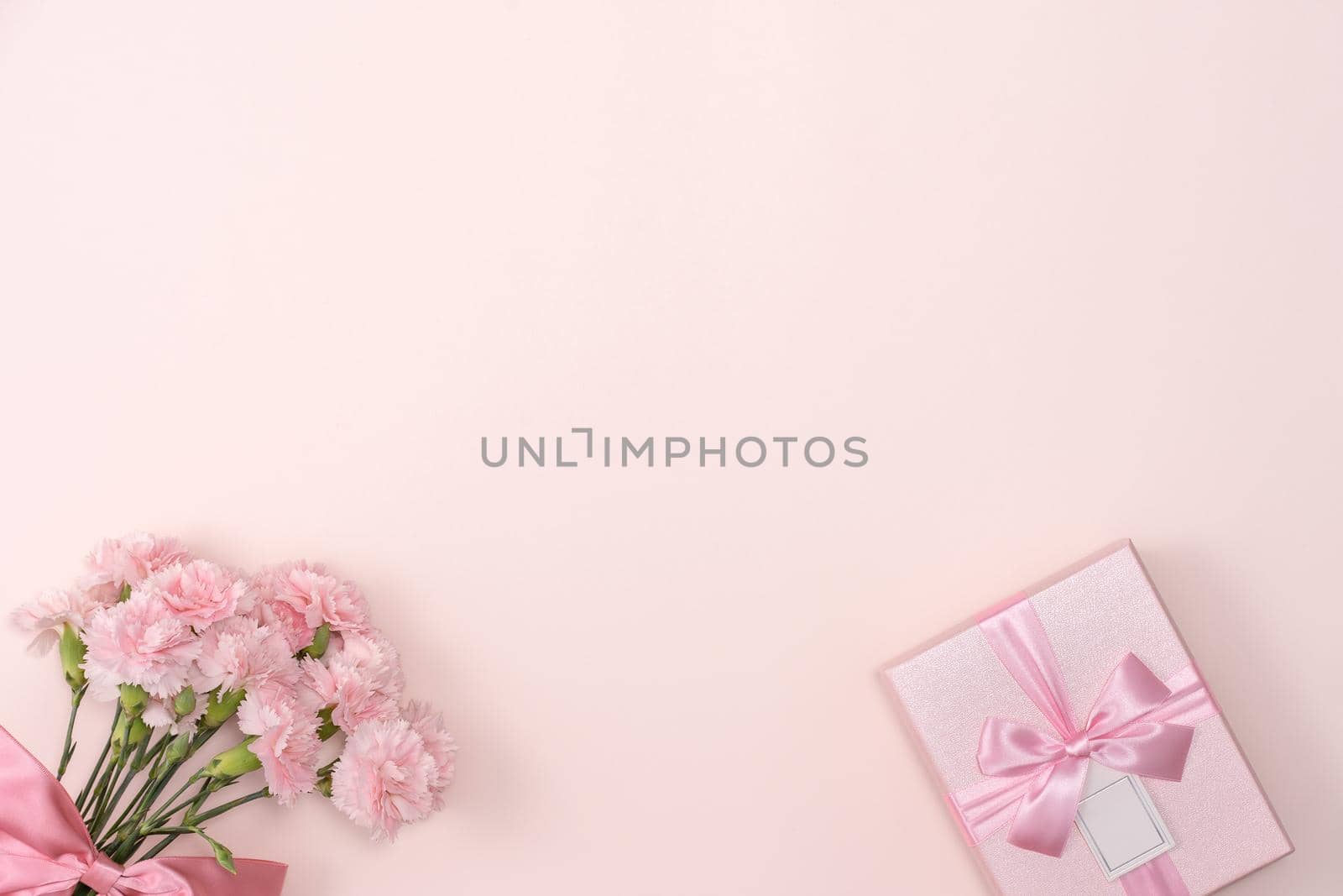 Mother's day background concept. Top view design of holiday greeting gift with carnation bouquet on bright pink table background