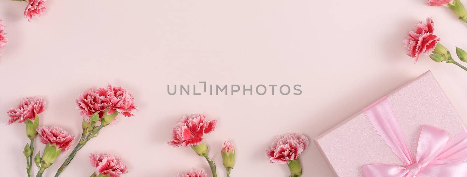 Mother's day background concept. Top view design of holiday greeting gift with carnation bouquet on bright pink table background