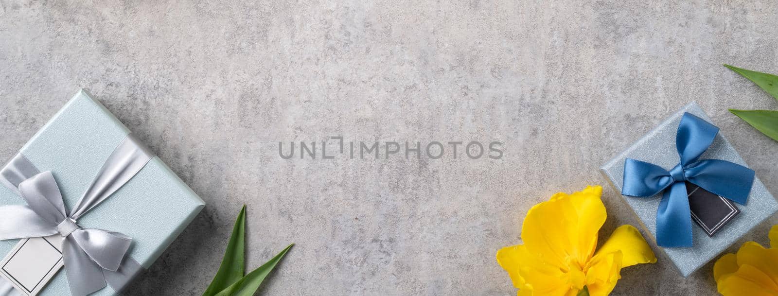 Mother's day background concept. Top view design of holiday greeting gift with yellow tulip bouquet on bright gray table background