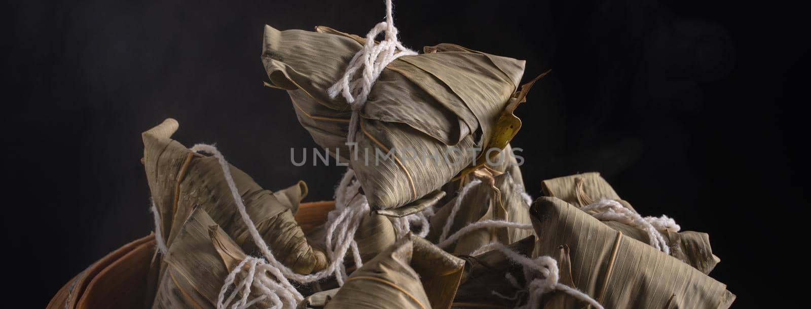 Zongzi rice dumpling for Chinese traditional Dragon Boat Festival (Duanwu Festival) over dark background.