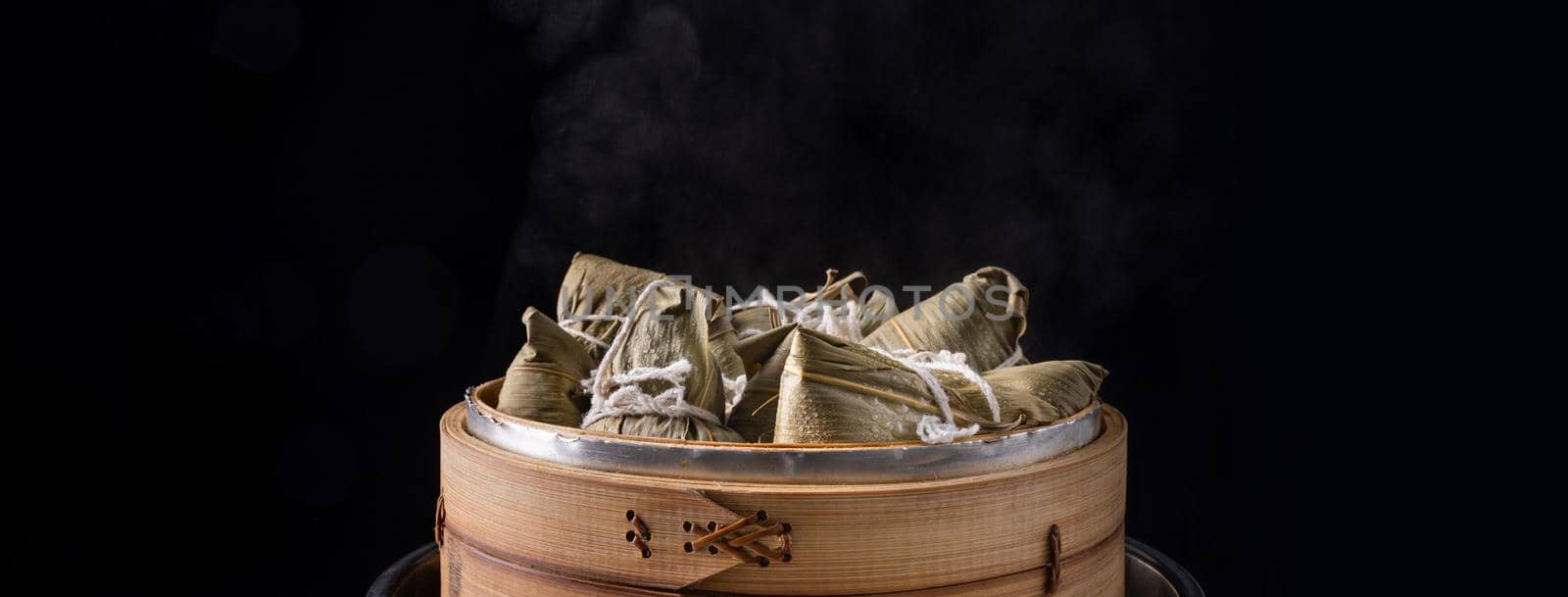 Zongzi rice dumpling for Chinese traditional Dragon Boat Festival (Duanwu Festival) over dark background.