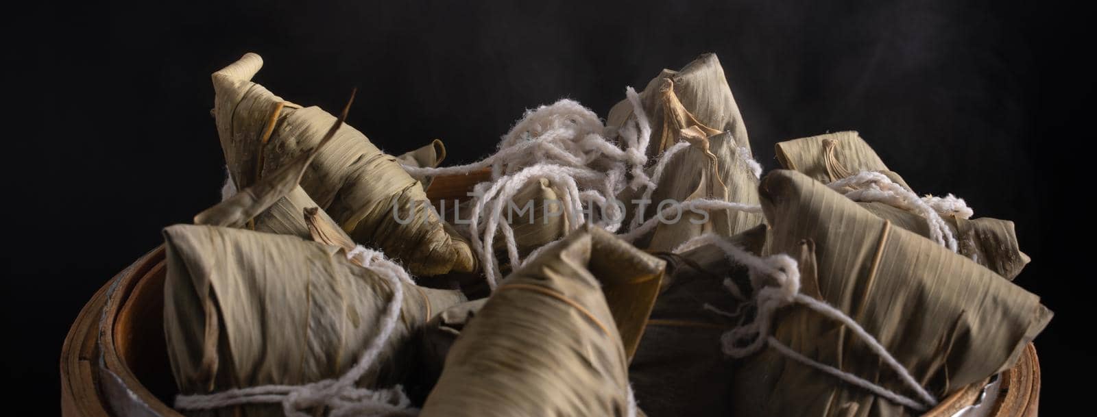 Zongzi rice dumpling for Chinese traditional Dragon Boat Festival (Duanwu Festival) over dark background.