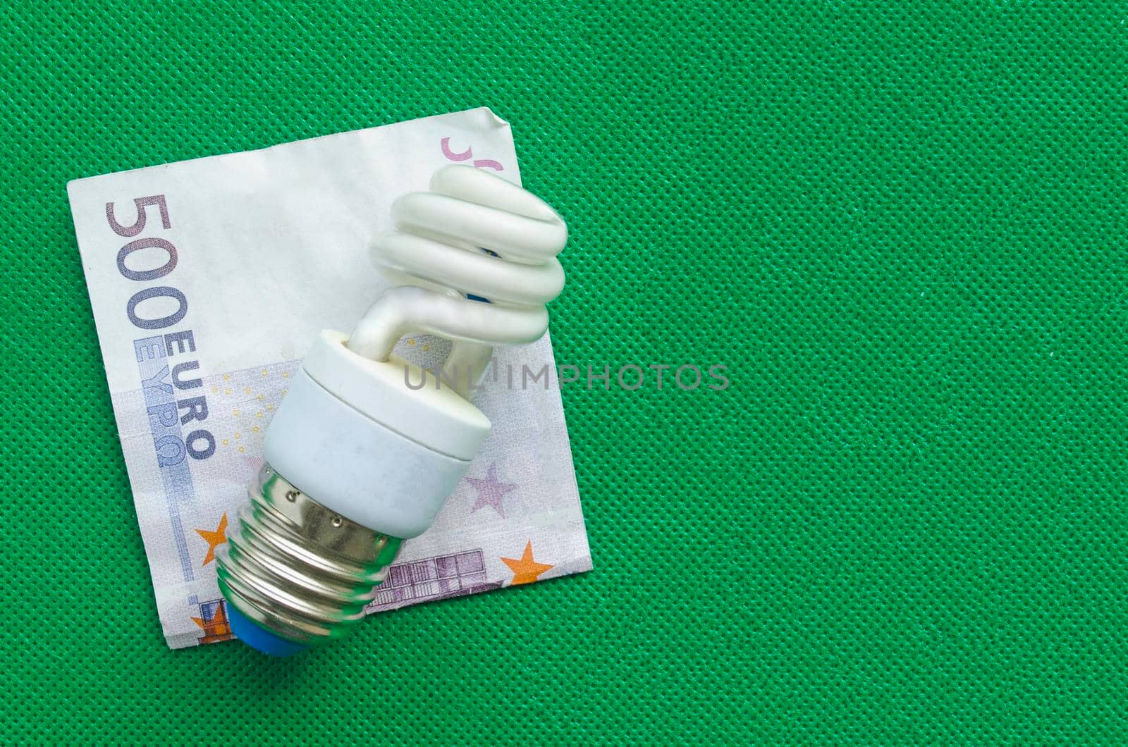 Energy-saving lamp and euro banknote on green background, copyspace. by andre_dechapelle