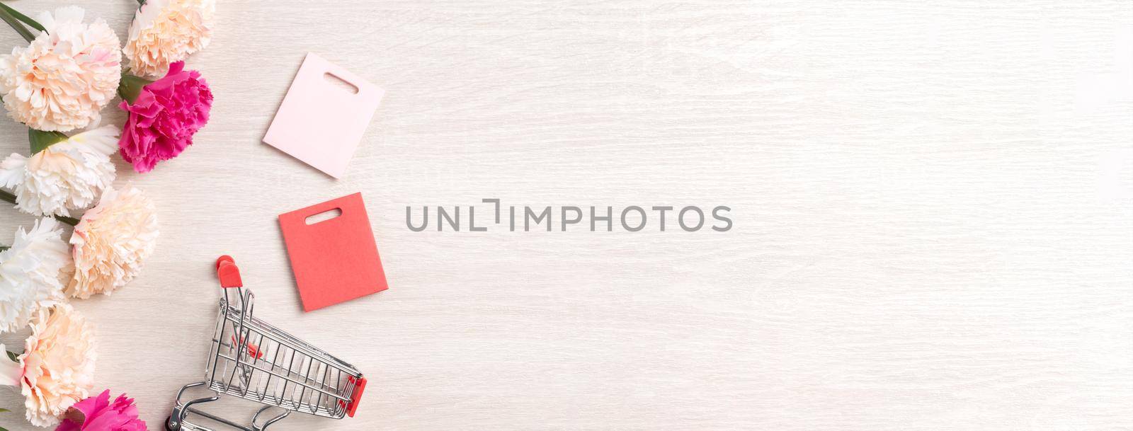 Design concept of Mother's Day greeting with carnation flower, holiday gift idea and shopping cart on wooden background.
