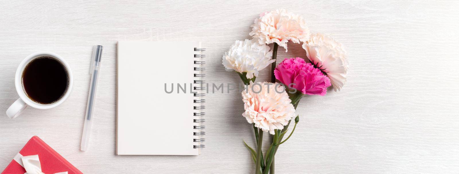 Design concpet of Mother's Day greeting with carnation flower, holiday gift idea and notebook diary on mother's desk background.