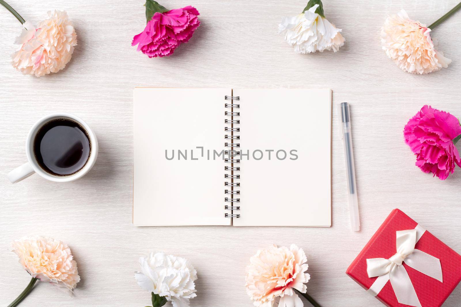 Design concpet of Mother's Day greeting with carnation flower, holiday gift idea and notebook diary on mother's desk background.