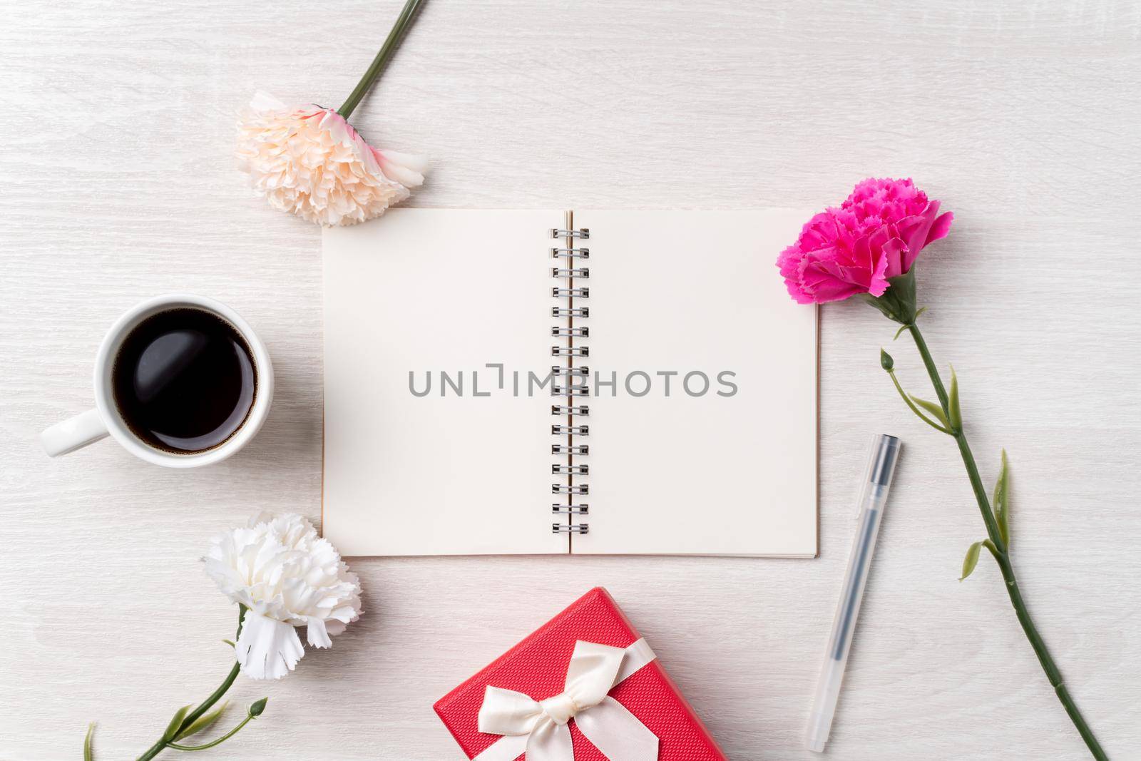 Design concpet of Mother's Day greeting with carnation flower, holiday gift idea and notebook diary on mother's desk background.