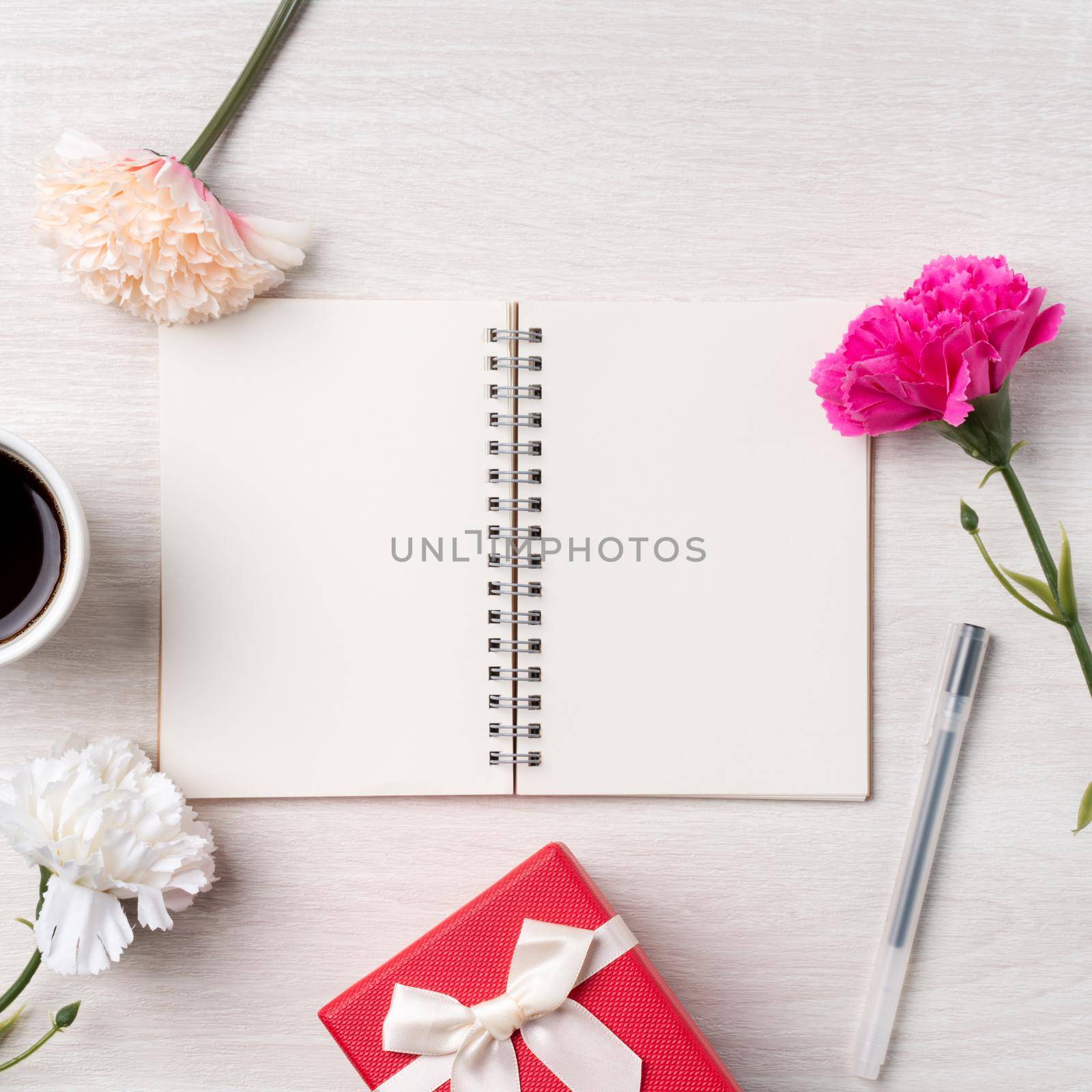Design concpet of Mother's Day greeting with carnation flower, holiday gift idea and notebook diary on mother's desk background.