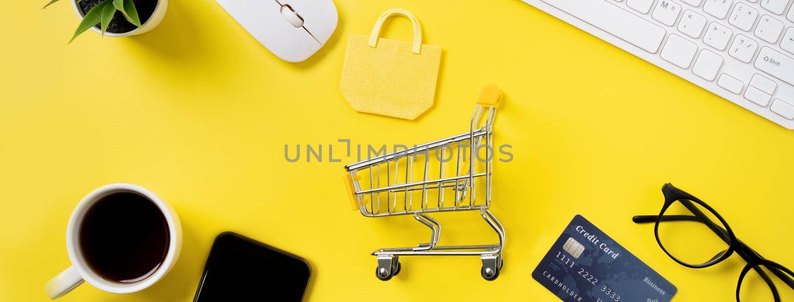 Top view of online shopping concept with credit card, smart phone and computer isolated on office yellow table background.