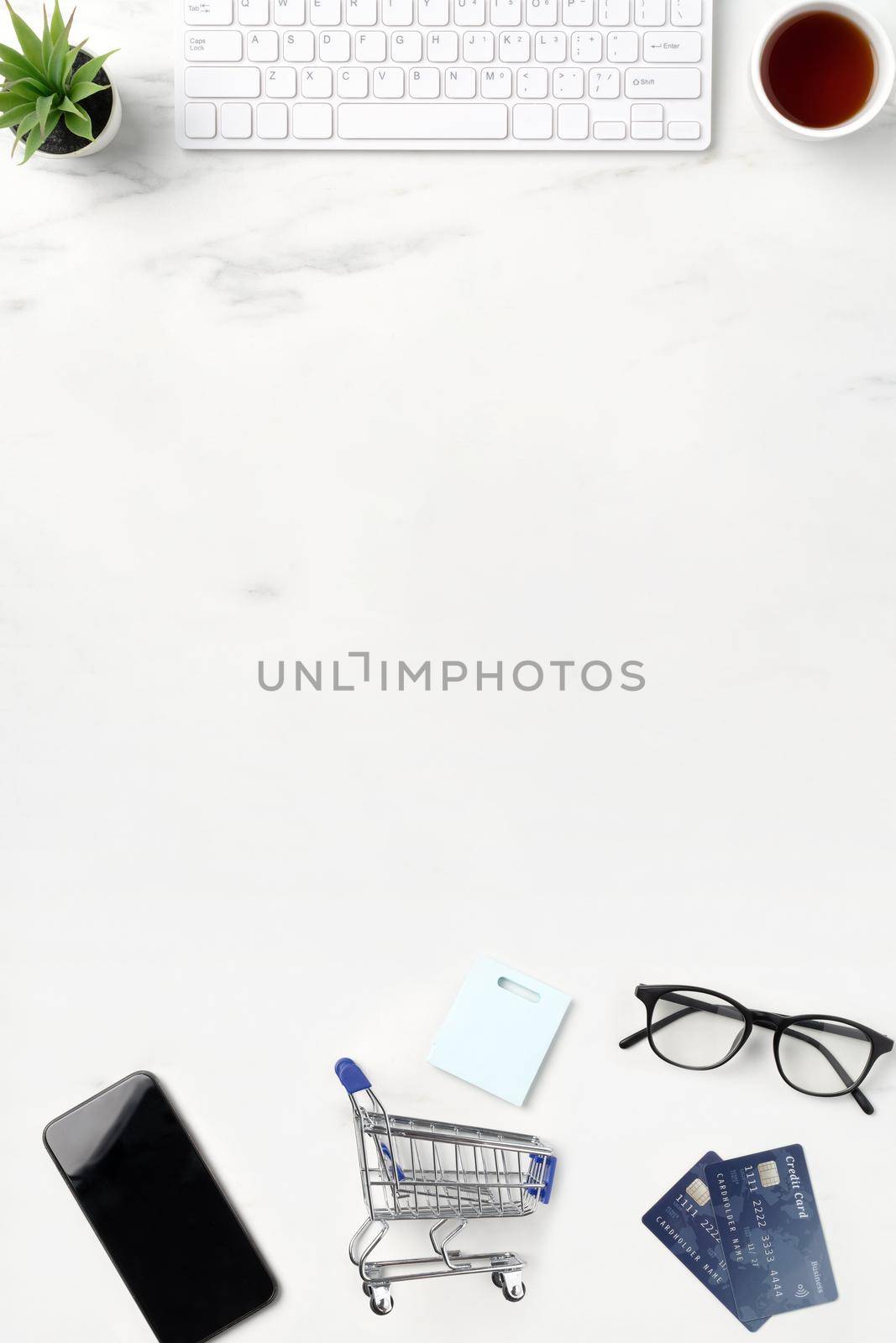 Top view of online shopping concept with credit card, smart phone and computer isolated on office marble white table background.