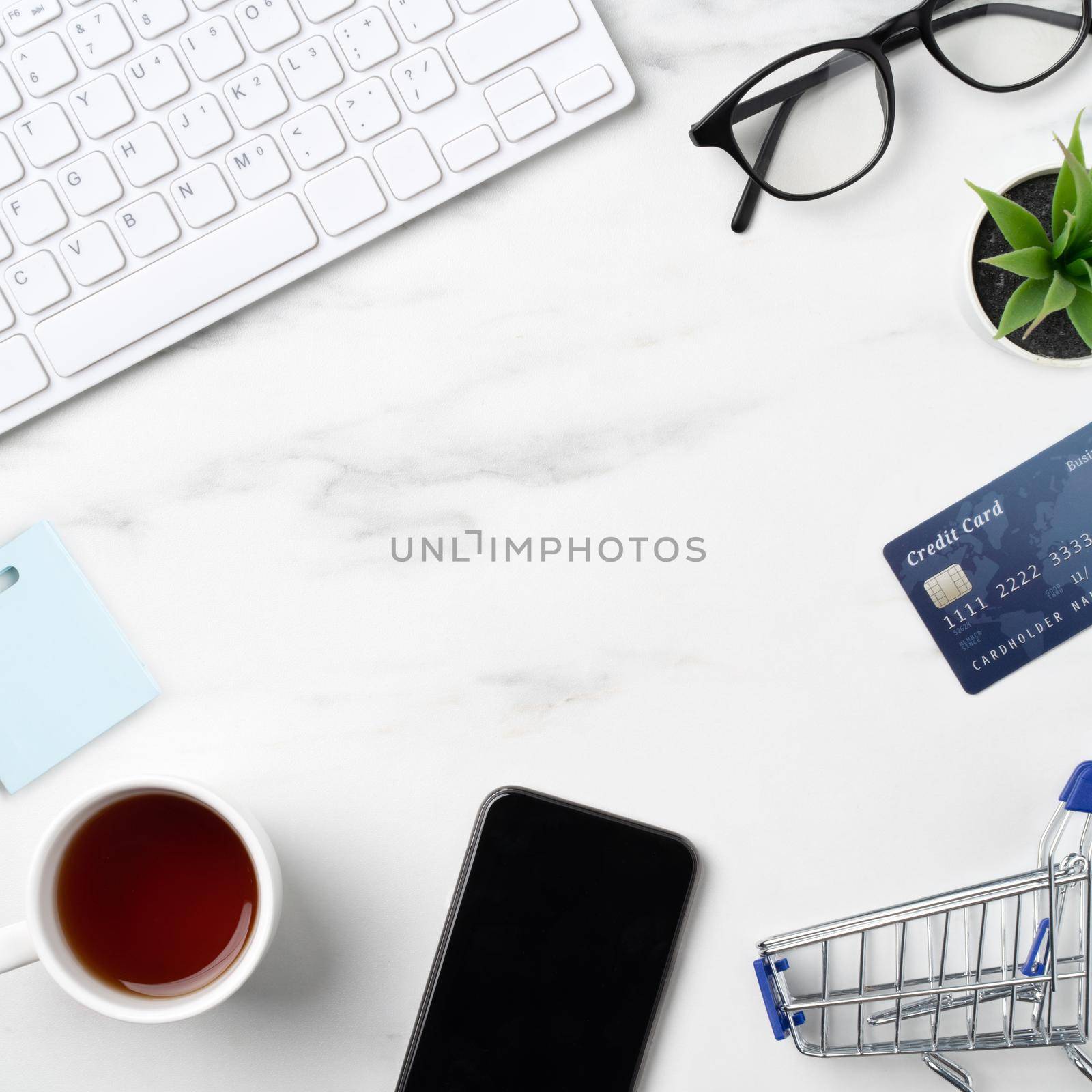 Top view of online shopping concept with credit card, smart phone and computer isolated on office marble white table background.
