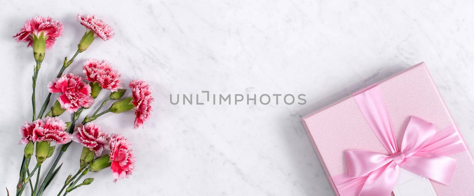 Concept of Mother's day holiday greeting gift design with carnation bouquet on white marble background