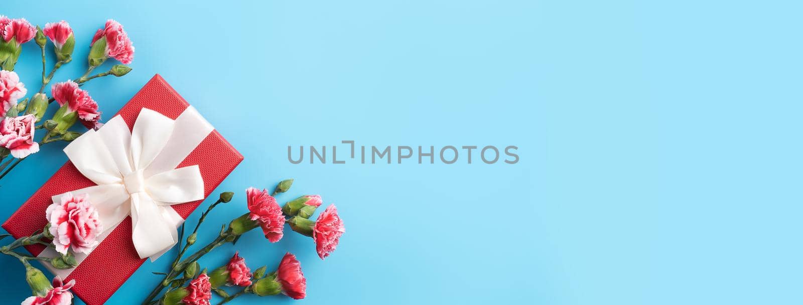 Concept of Mother's day holiday greeting gift design with carnation bouquet on bright blue table background