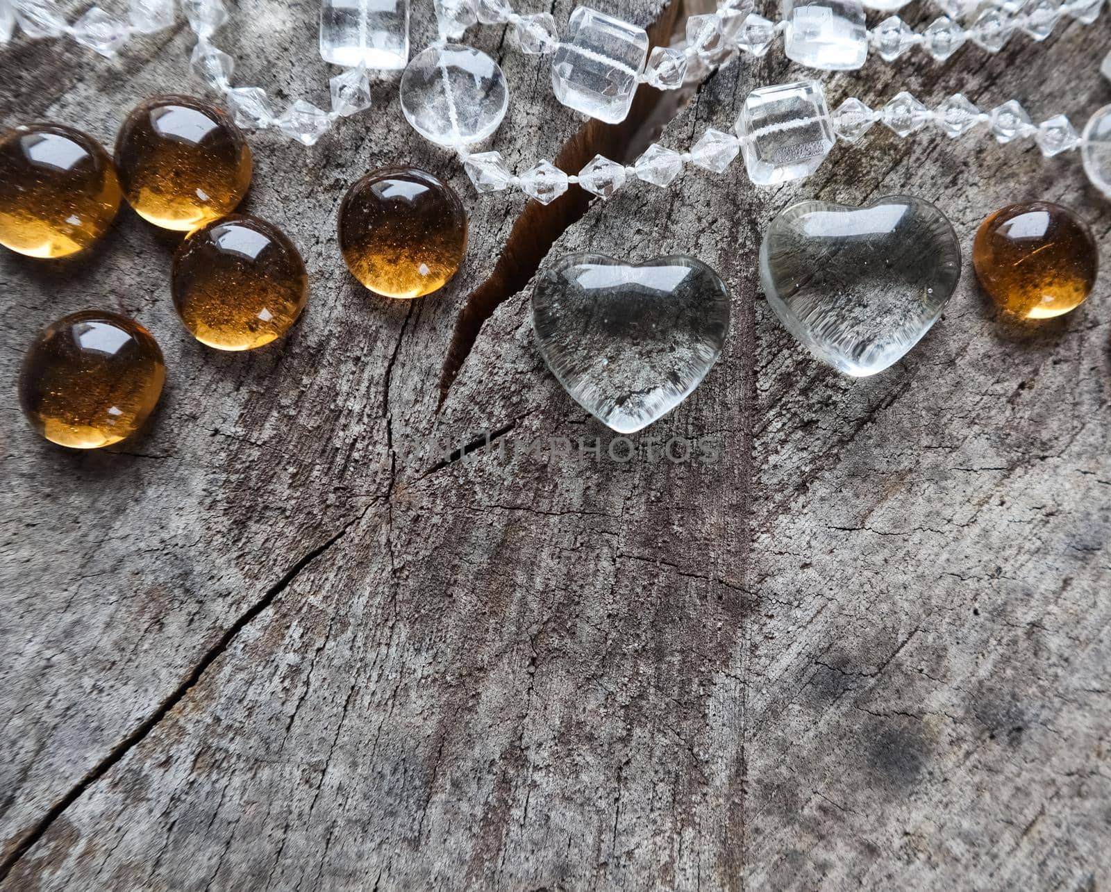 Two transparent hearts and beads on the rough surface of an old stump. Perfect Valentine's Day greeting card background.