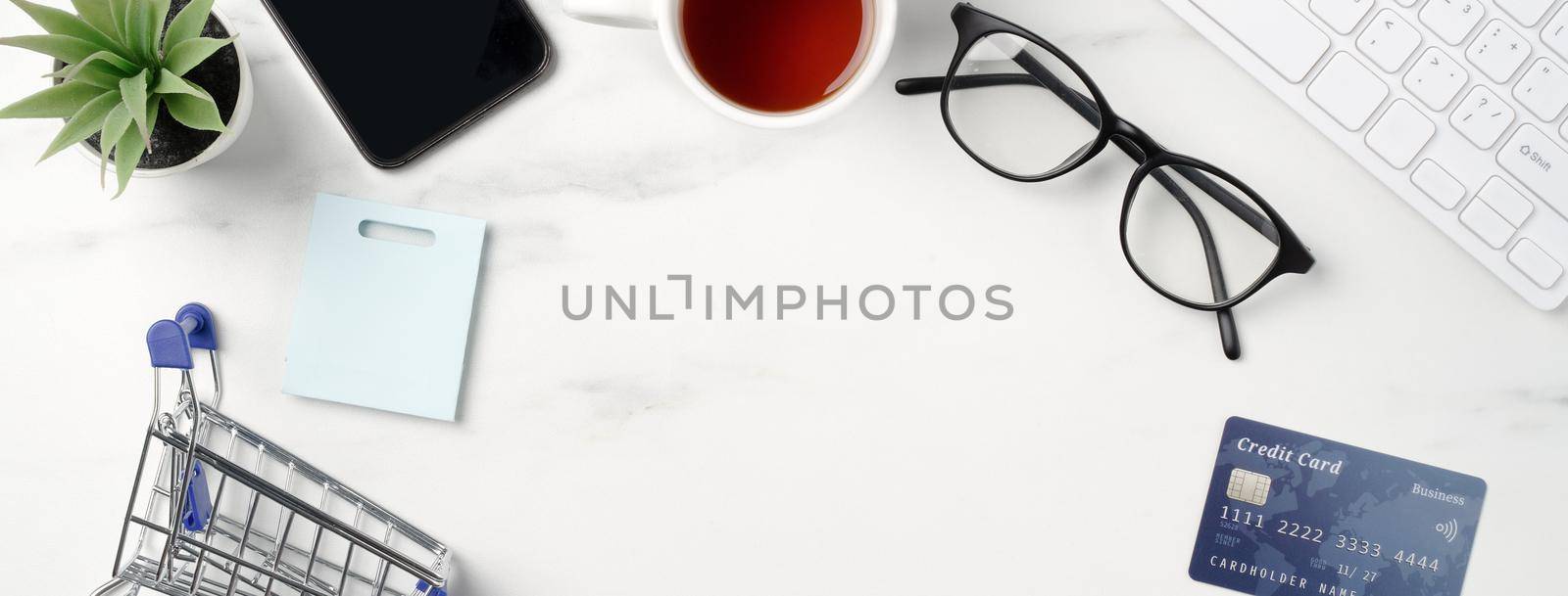 Top view of online shopping concept with credit card, smart phone and computer isolated on office marble white table background.