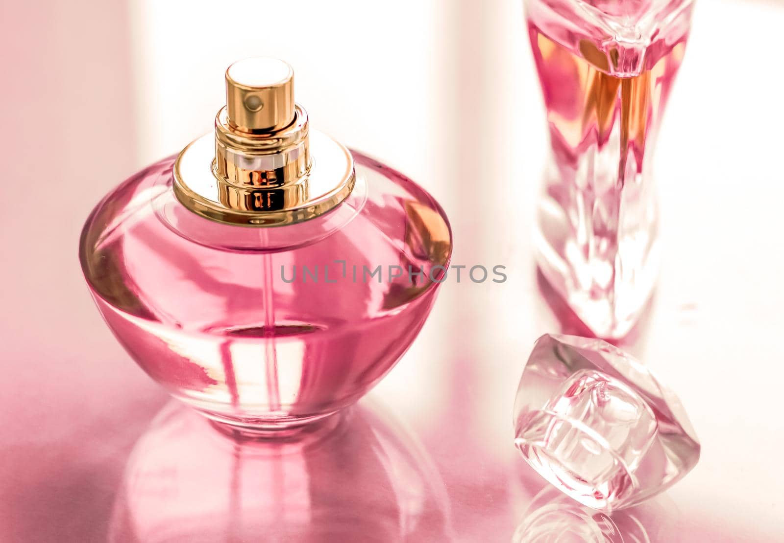 Perfumery, spa and branding concept - Pink perfume bottle on glossy background, sweet floral scent, glamour fragrance and eau de parfum as holiday gift and luxury beauty cosmetics brand design