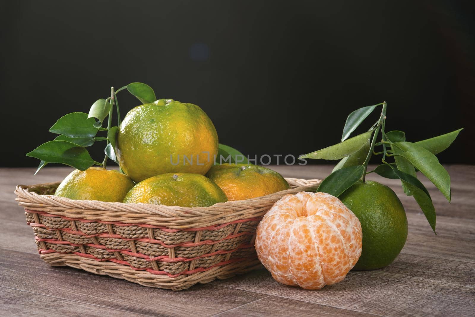 Fresh green tangerine mandarin orange with fresh leaves on dark wooden table background harvest concept.