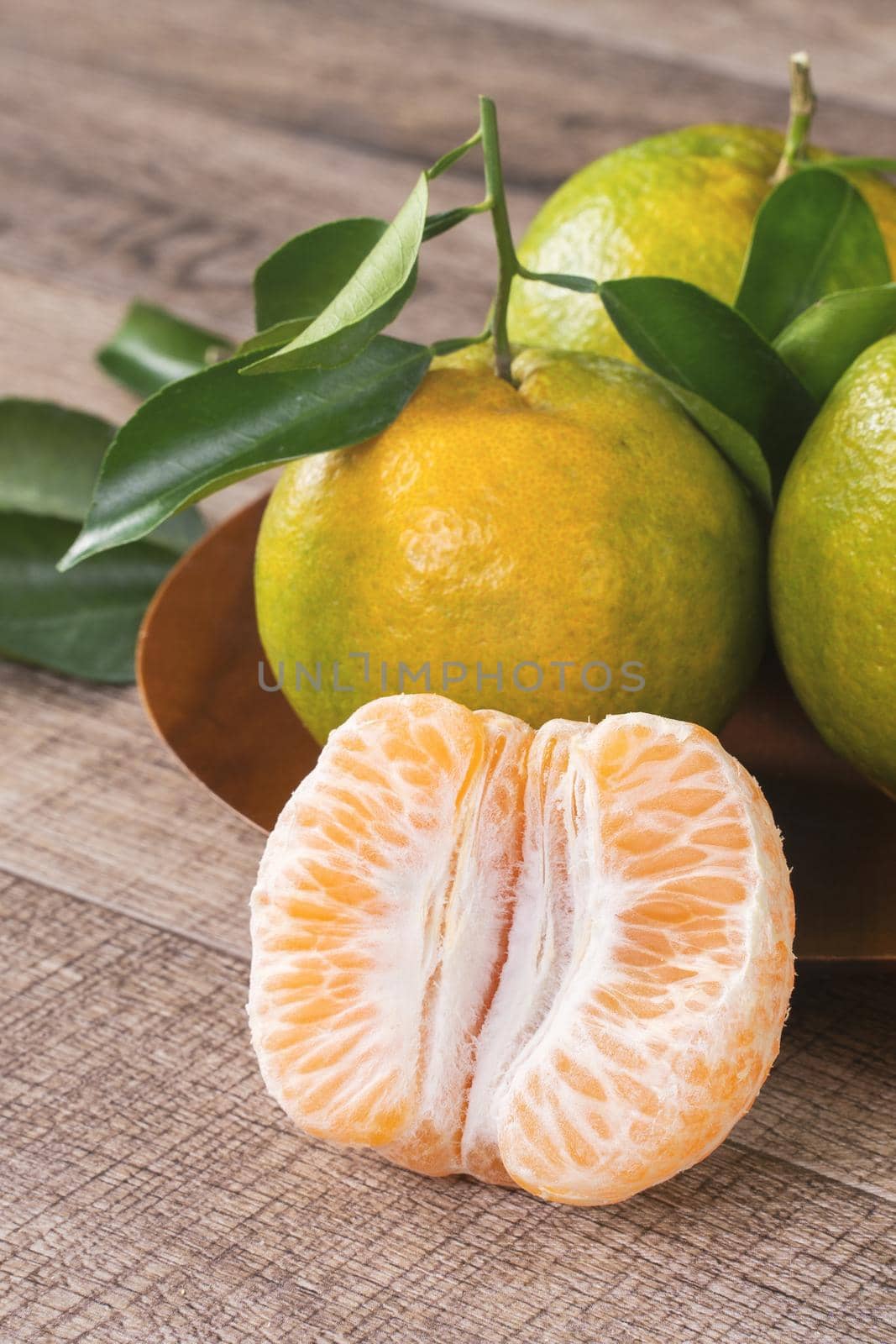 Fresh green tangerine mandarin orange with fresh leaves on dark wooden table background harvest concept.