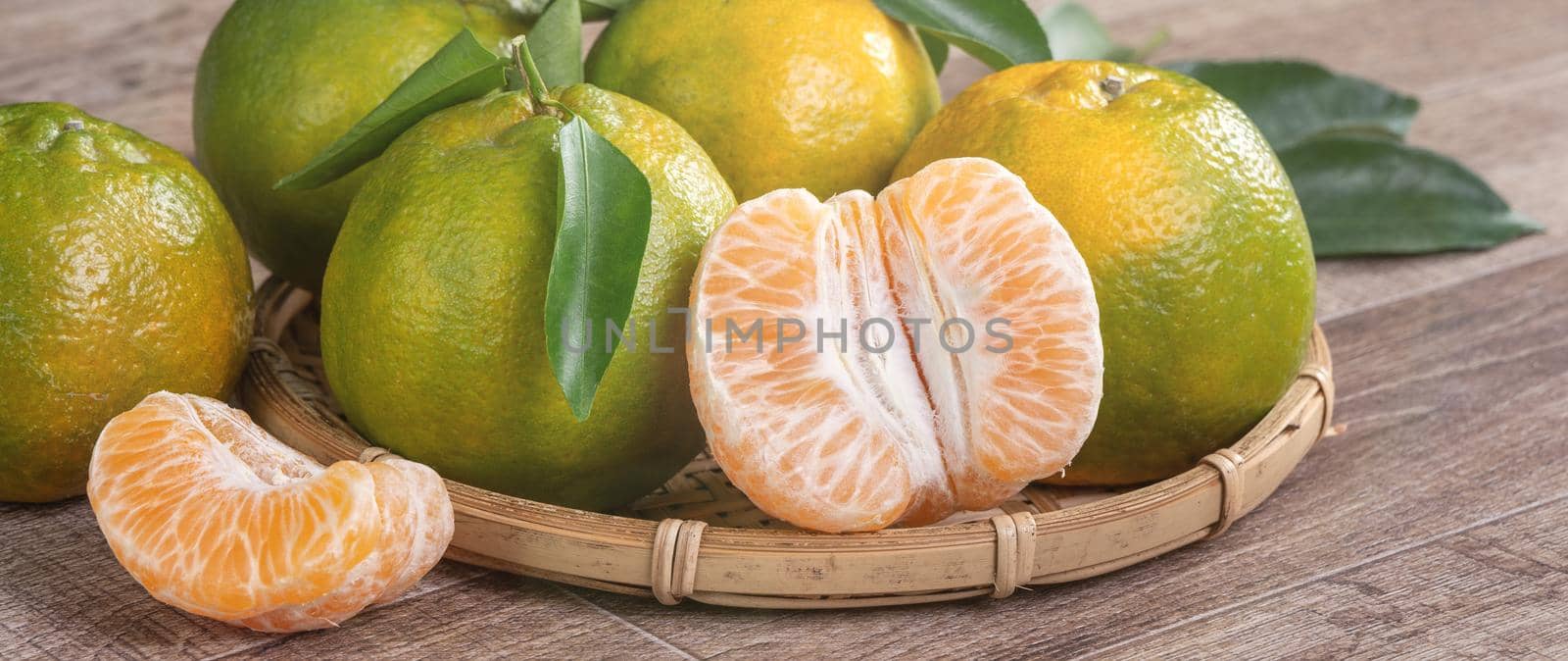 Fresh green tangerine mandarin orange on dark wooden table background. by ROMIXIMAGE