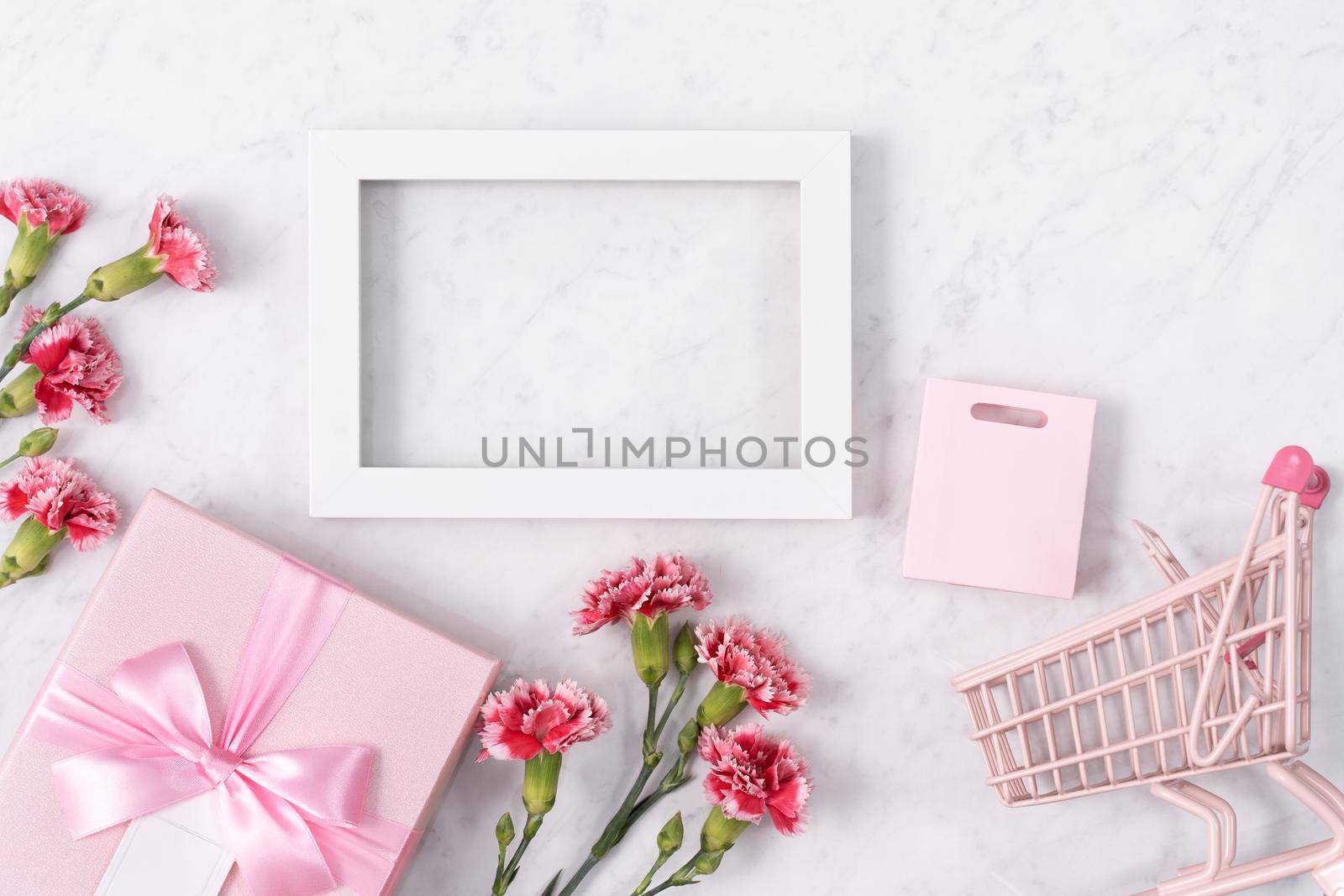 Concept of Mother's day holiday greeting design with carnation bouquet and gift on white marble background