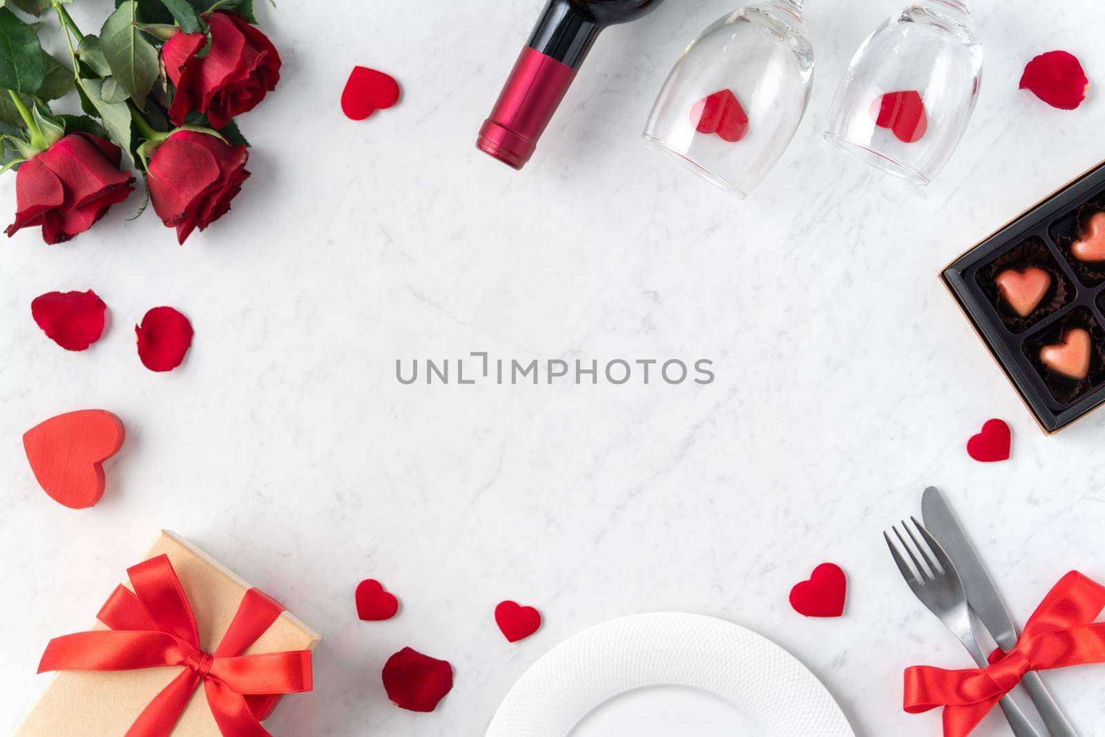 White plate with red rose flower on marble white table background for Valentine's Day dating holiday meal concept.