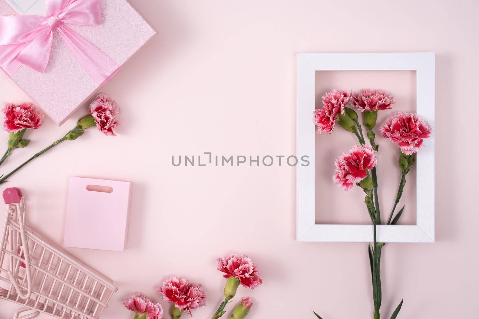 Concept of Mother's day holiday greeting design with carnation bouquet and gift on pink background