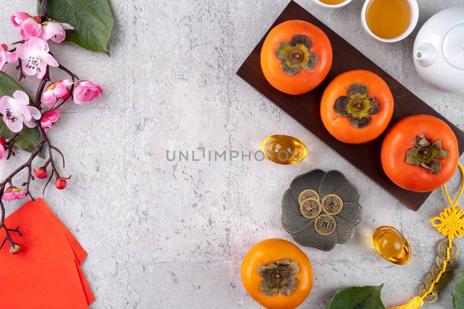 Fresh persimmons on gray table background for Chinese new year fruit design, words on the golden coin means the Dynasty name it made.