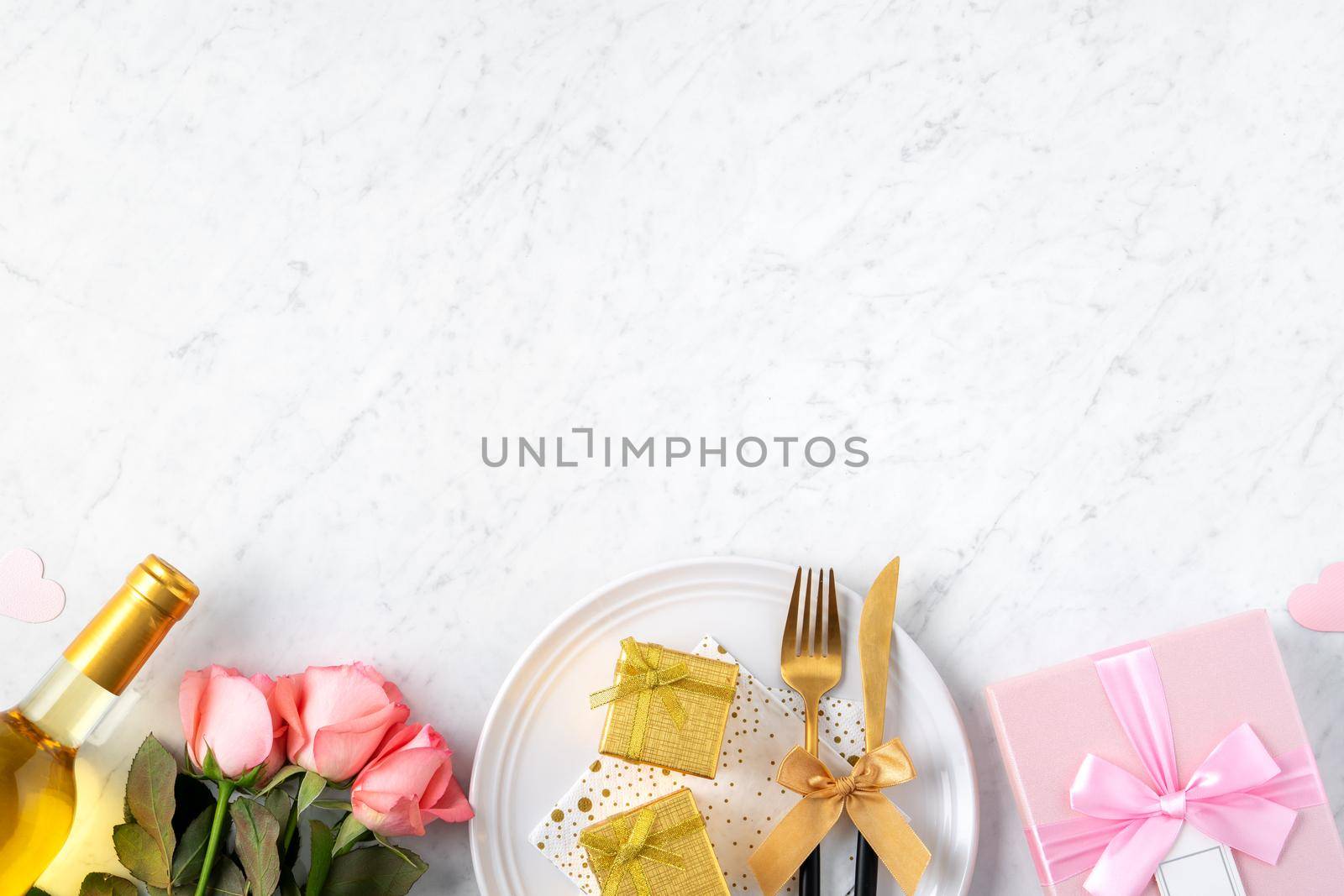 White plate with gift and pink rose flower on marble white table background for Valentine's Day special holiday dating meal concept.