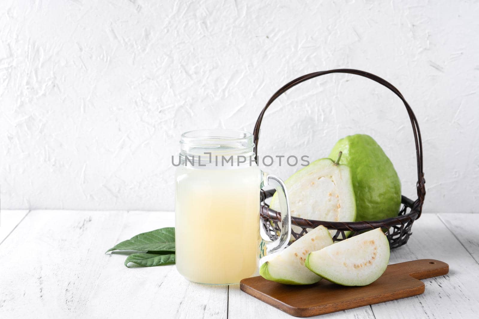Delicious beautiful guava fruit with fresh juice set isolated on bright white wooden table background, close up.