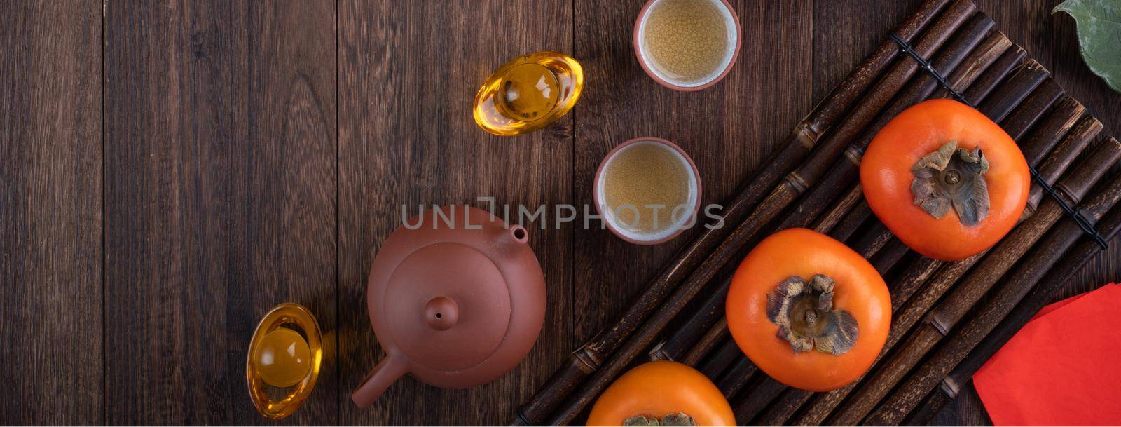 Top view of fresh sweet persimmons kaki with leaves on wooden table background for Chinese lunar new year fruit design concept, the word means blessing is coming.