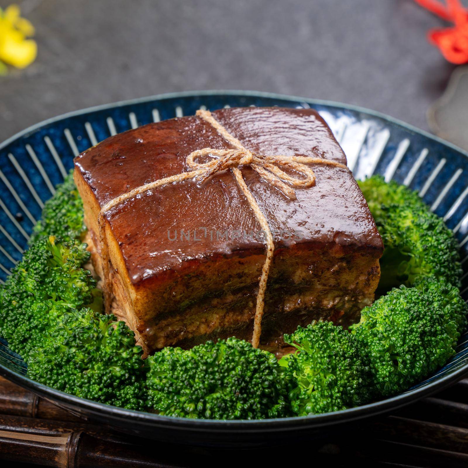 Dong Po Rou (Dongpo pork meat) in a beautiful blue plate with green broccoli vegetable, traditional festive food for Chinese new year cuisine meal, close up.
