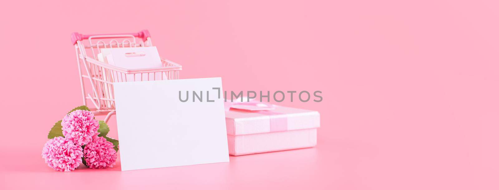 Mother's Day holiday gift design concept, pink carnation flower bouquet with wrapped gift box isolated on pink background, copy space.