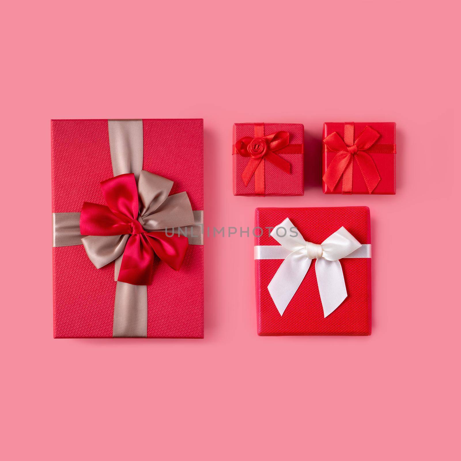 Beautiful gift box wrapped with ribbon bow on pastel pink background.