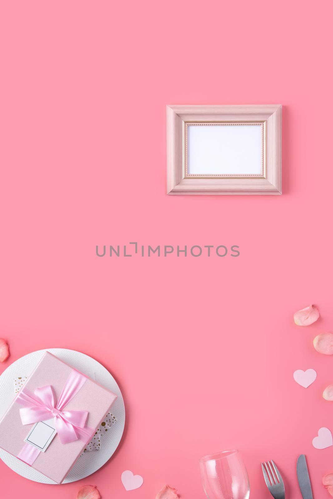 Valentine's Day design concept background with pink petals and gift box on pink background